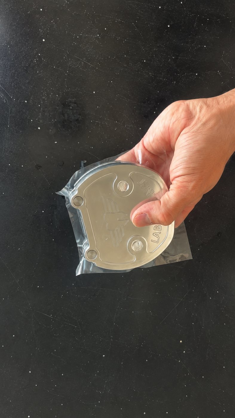 Hand holding a LabPilot flask lid wrapped in a clear plastic packing sheet